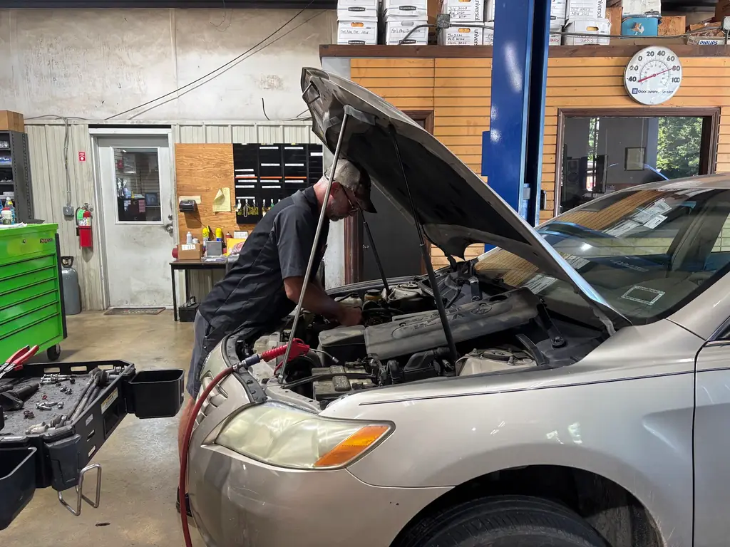 Technician working under the hood of a sedan at Baxley's Auto Repair