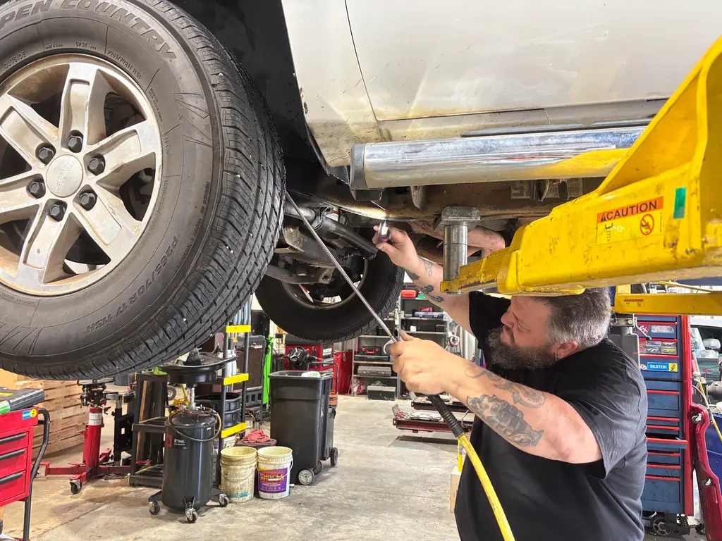 Technician working underneath a lifted pickup at Baxley's Auto Repair