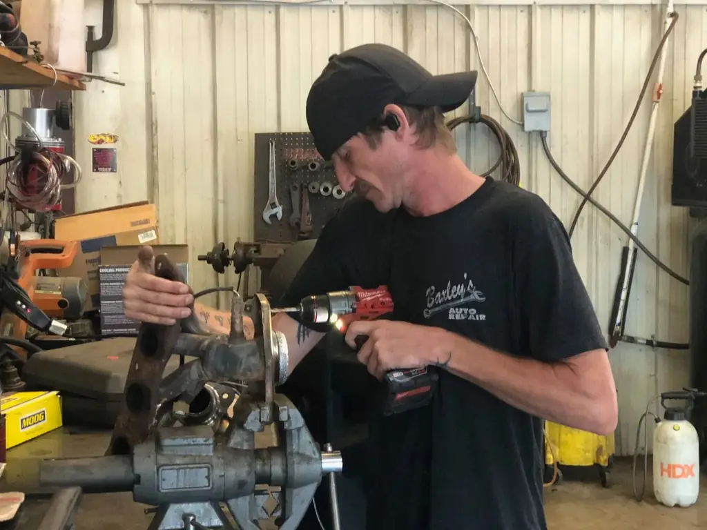 A technician at the bench vise wearing a Baxley's Auto Repair shirt